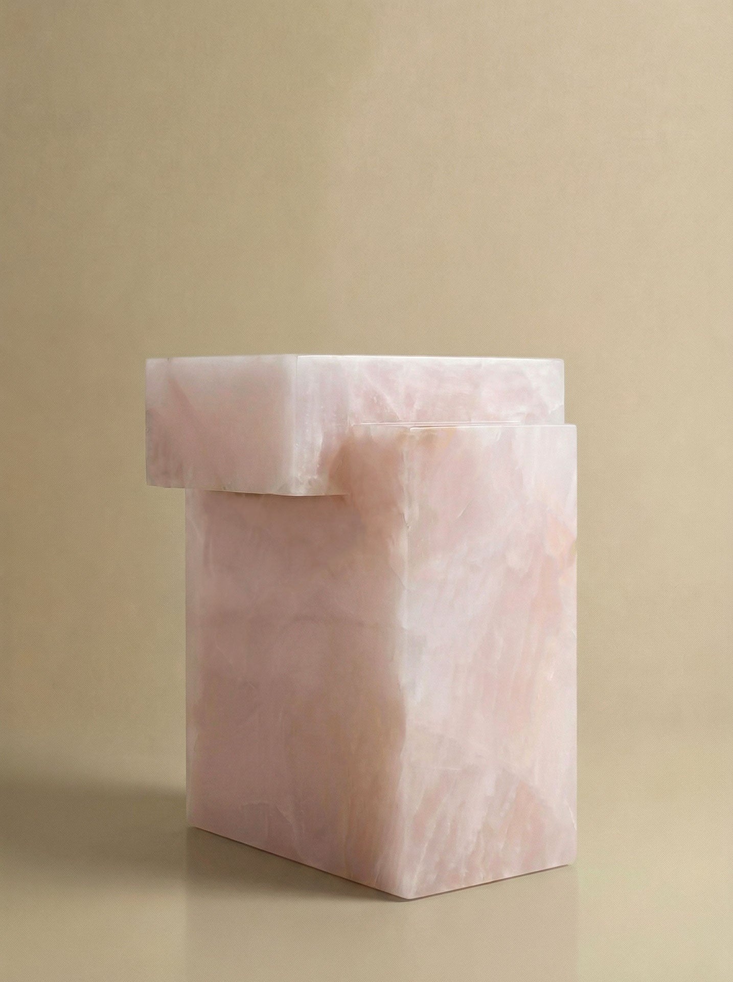 Three-quarter view of pink onyx table displaying natural stone beauty and elegant curved silhouette