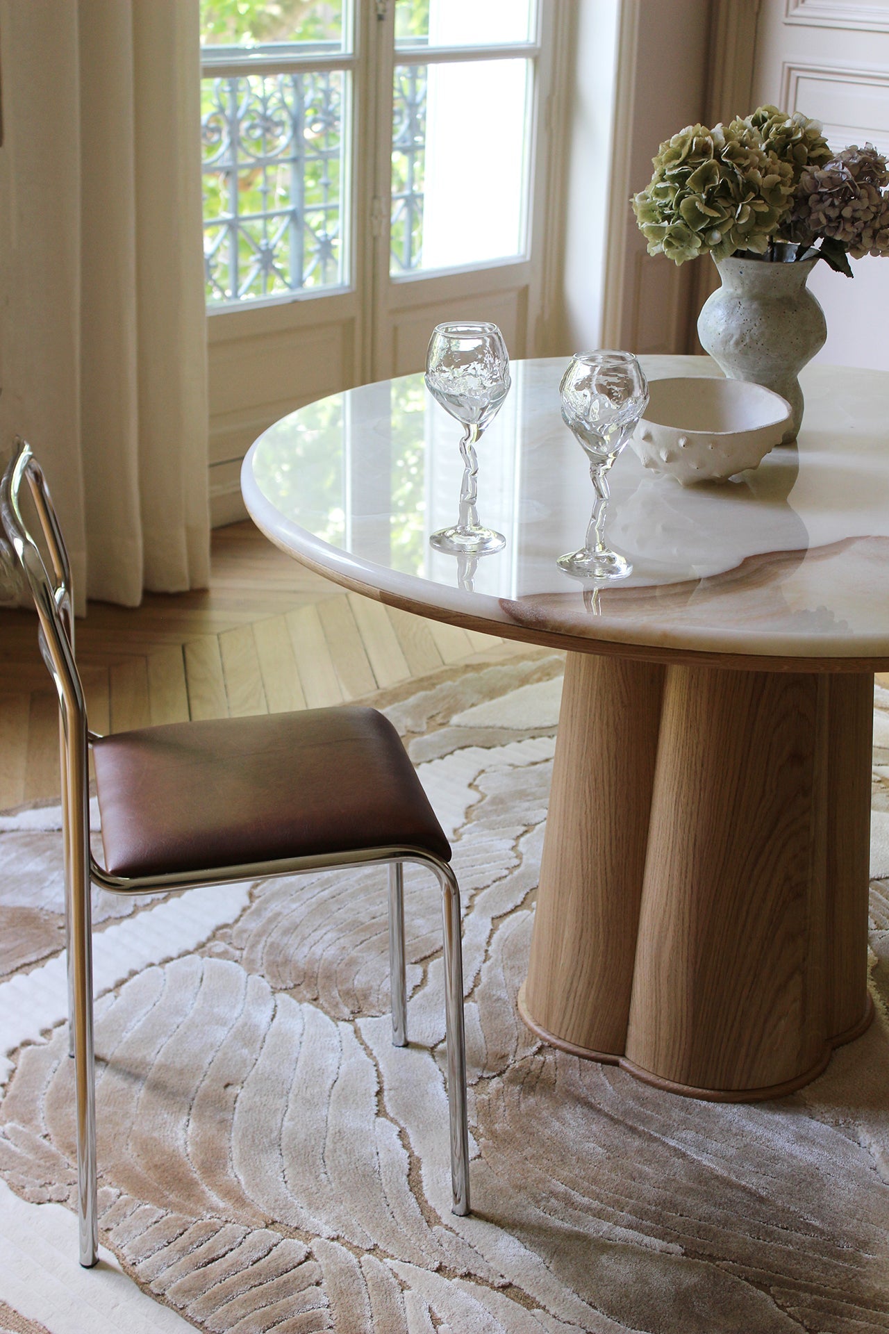 Close-up of Poli dining table oak wood base with honey finish and vanilla onyx marble top