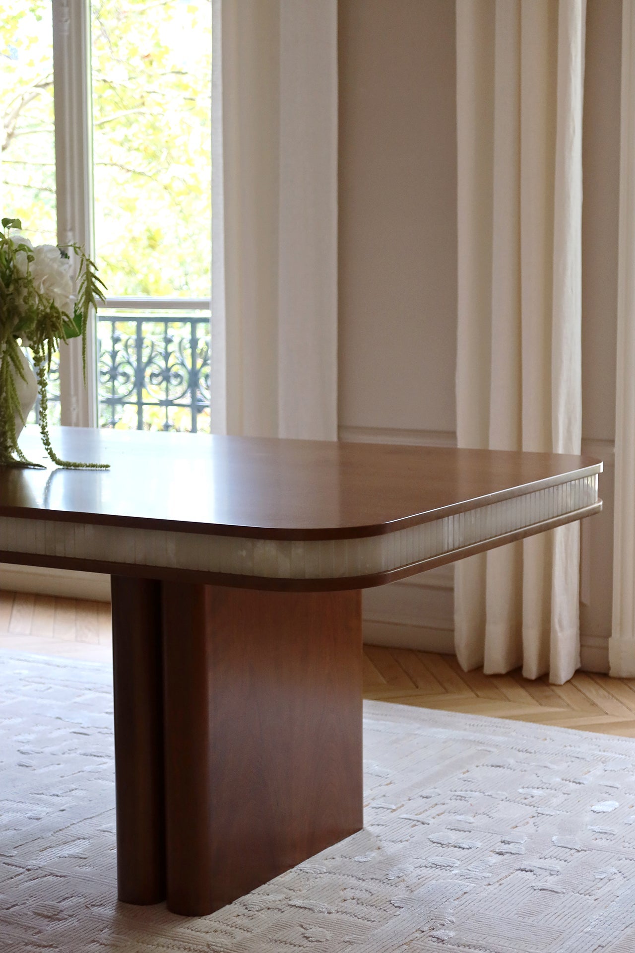 Three-quarter view of Doppio dining table showcasing wood and white onyx material harmony
