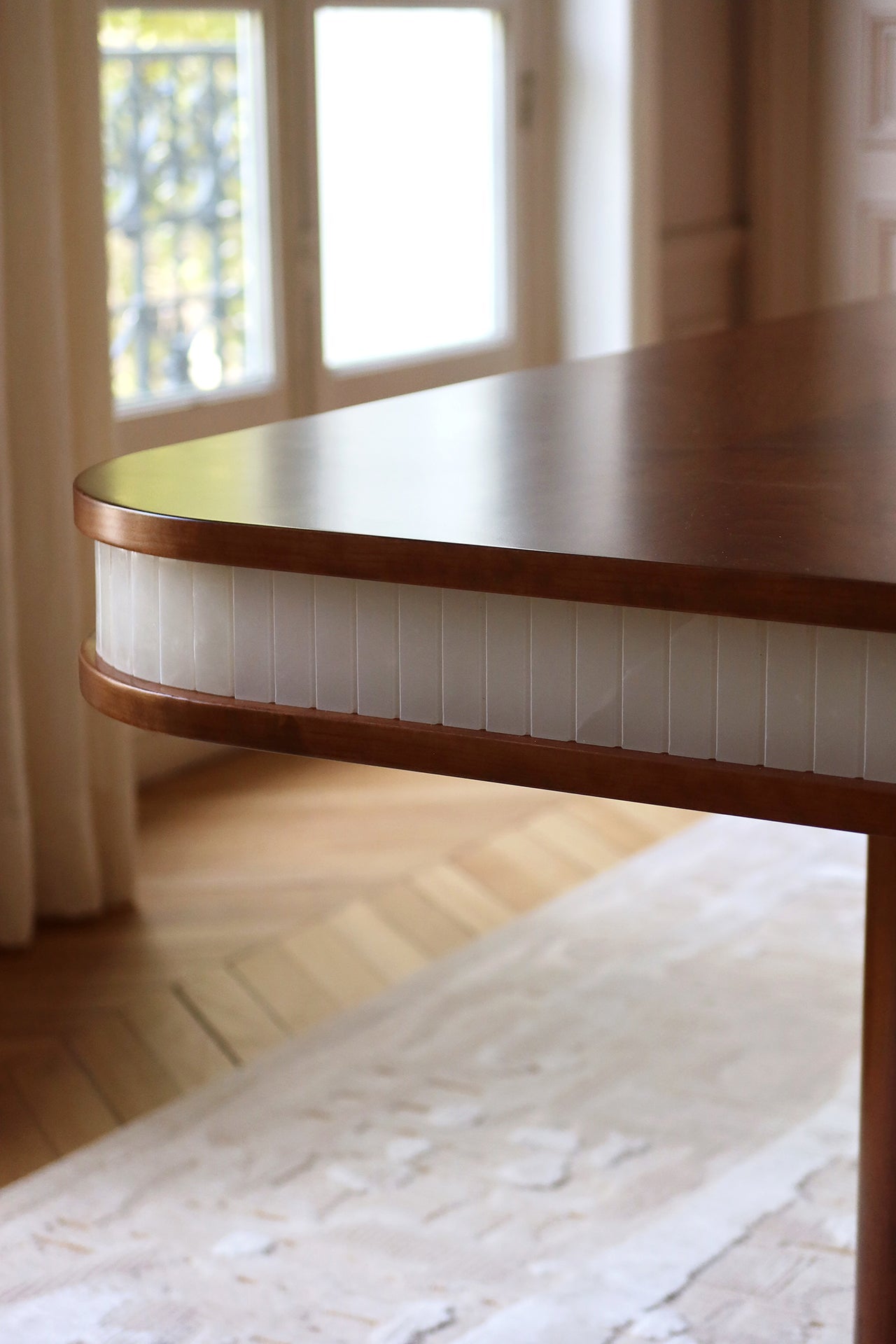 Profile view of Doppio dining table emphasizing clean modern lines of wood and white onyx design